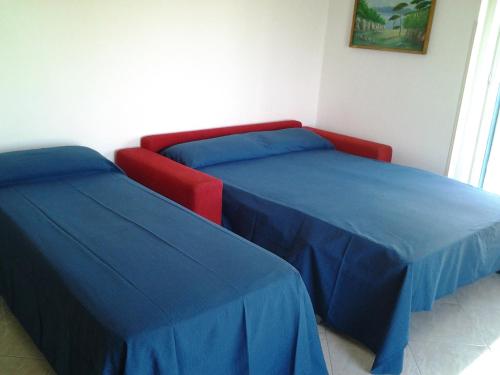 two beds with blue and red covers in a room at Hotel Conca d'Oro in Stalettì