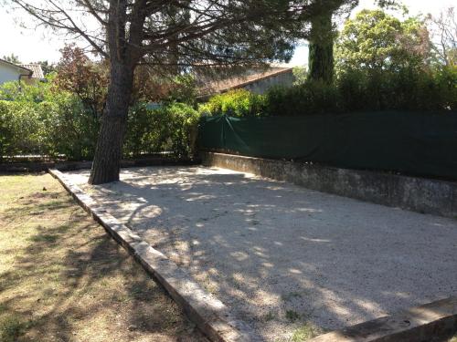a tree in a yard next to a fence at Le Petit Manoir Hotel Provence in Les Angles Gard