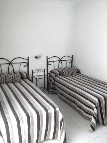two beds with striped sheets in a room at Hotel Marítimo Urban in Alicante