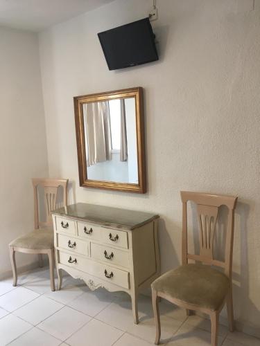 a dresser with two chairs and a mirror on a wall at Hotel Marítimo Urban in Alicante