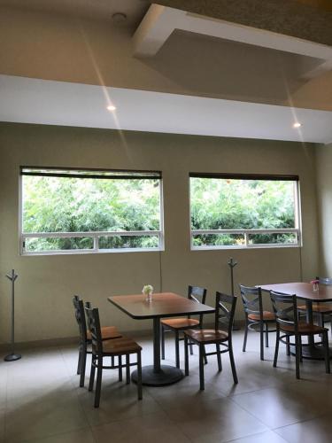 una sala da pranzo con due finestre, tavoli e sedie di Hotel & Villas Panamá a Città del Messico