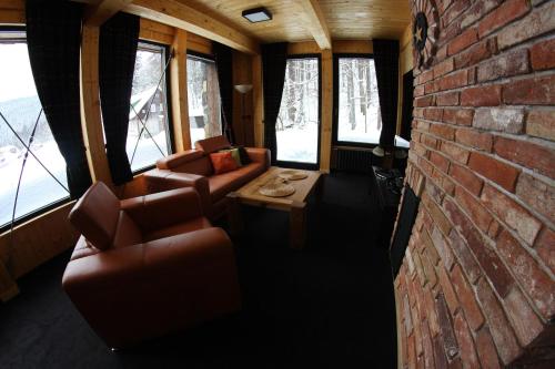 a room with couches and a brick wall and windows at Krakonošova Dílna "WOODHAUS" in Špindlerův Mlýn
