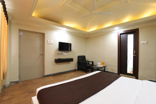 a bedroom with a bed and a tv on the wall at Hotel Loyal Residency in Jamnagar
