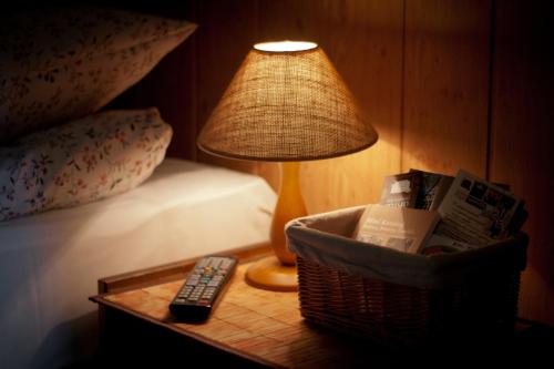 a lamp on a table next to a bed with a remote control at Rancho Ślężański Młyn in Szczepanów