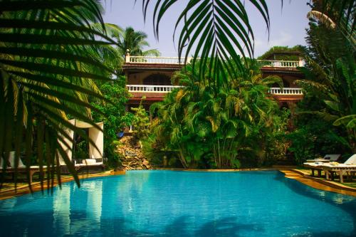 a swimming pool in a resort with palm trees at Papa Jolly Eco Resort-Near Morjim Beach in Morjim