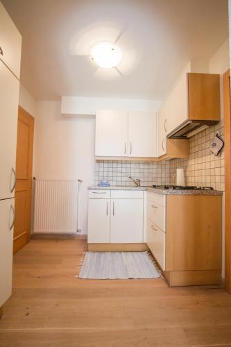 an empty kitchen with white cabinets and a floor at Mutznhof in Dobbiaco