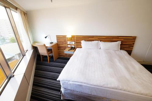 a bedroom with a large white bed and a desk at Dynasty Hotel in Tainan