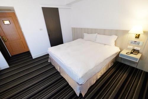 a hotel room with a bed and a night stand at Dynasty Hotel in Tainan