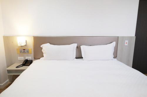 a bed with two white pillows and a telephone at Dynasty Hotel in Tainan