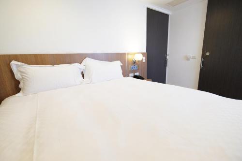 a large white bed in a hotel room at Dynasty Hotel in Tainan