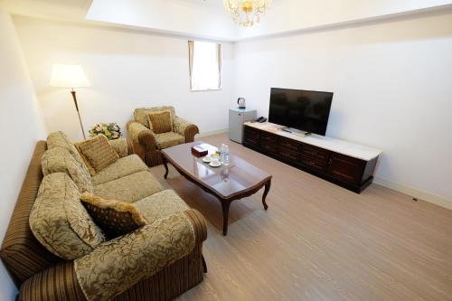 a living room with a couch and a tv at Dynasty Hotel in Tainan
