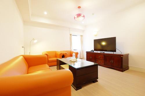 a living room with orange furniture and a flat screen tv at Dynasty Hotel in Tainan