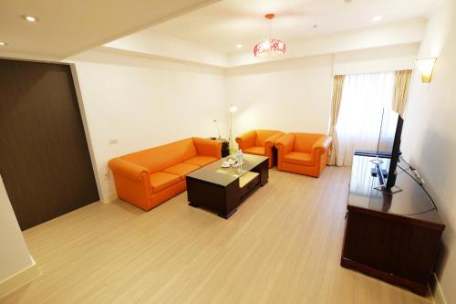 a living room with orange furniture and a television at Dynasty Hotel in Tainan