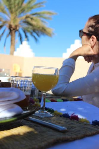 a woman sitting at a table with a glass of wine at Riad Hiba in Foum Zguid