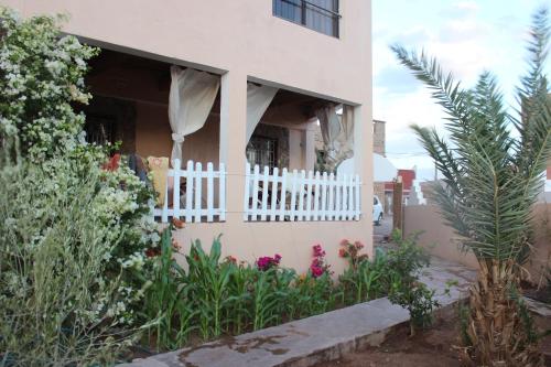 a house with a white fence and some flowers at Riad Hiba in Foum Zguid