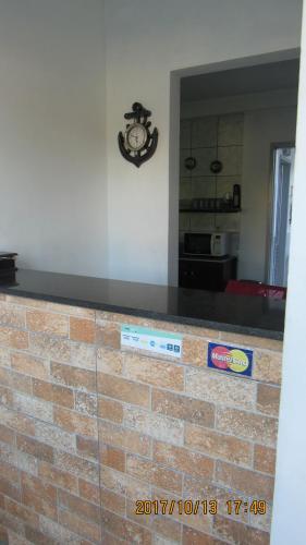 un mostrador de ladrillo en una cocina con un reloj en la pared en Pousada Girassol, en Matinhos