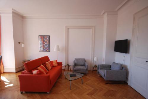 a living room with a red couch and two chairs at Appartements in zentraler Lage in Tübingen