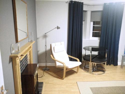 a living room with a white chair and a table at 456js Edinburgh Self-Catering Apartment in Edinburgh