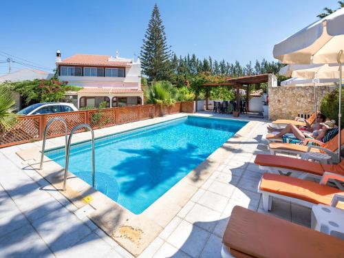 a swimming pool with people sitting on chairs next to a house at Apartamentos Flor da Laranja, Albufeira by AlgarveBlossom in Albufeira