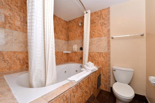 a bathroom with a tub and a toilet at Americas Best Value Inn & Suites-East Bakersfield in Bakersfield
