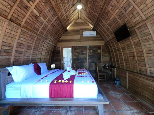 a bedroom with a large bed in a wooden room at Ryanbagus Guest House in Canggu