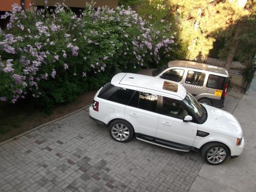 a white car parked on a sidewalk next to some bushes at Vila Silia in Skopje