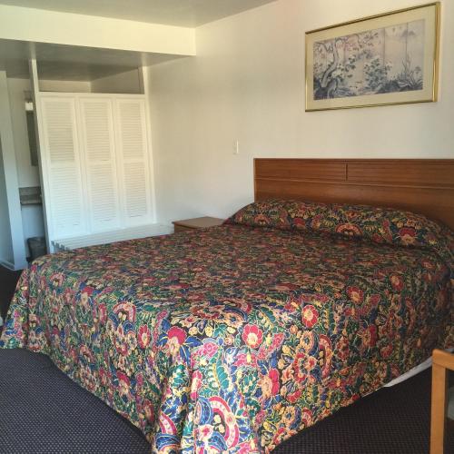 a bedroom with a bed with a colorful bedspread at Valley Motel Pittsburgh in Harmarville