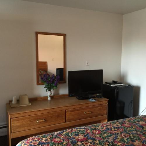 a bedroom with a dresser with a television on it at Valley Motel Pittsburgh in Harmarville