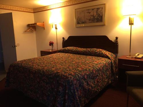a hotel room with a bed and two lamps at Valley Motel Pittsburgh in Harmarville