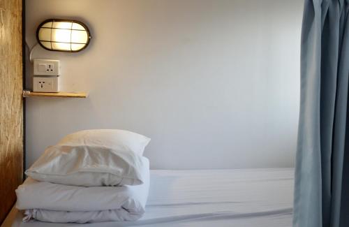 a bedroom with a bed with white pillows and a mirror at Old Man Captain in Tainan