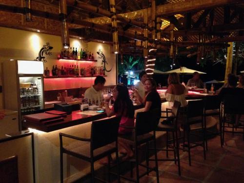 a group of people sitting at a bar in a restaurant at Pyramid Resort in Panglao