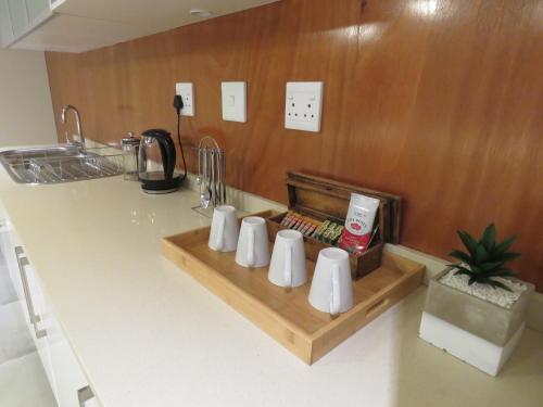 a kitchen counter with white cups on a wooden shelf at The Executive - Exclusive Self-Catering Apartments - Ezulwini in Ezulwini