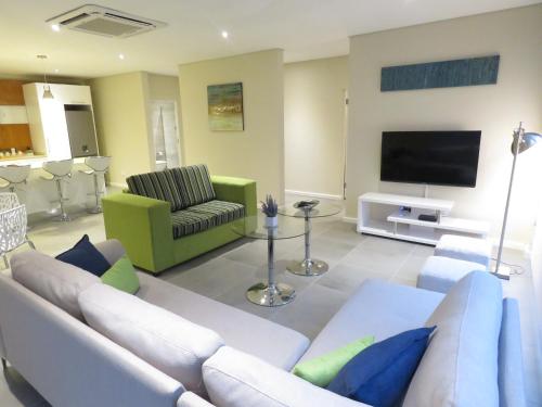 a living room with a white couch and a flat screen tv at The Executive - Exclusive Self-Catering Apartments - Ezulwini in Ezulwini