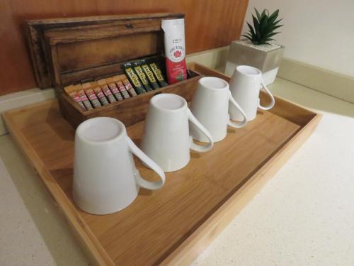 a group of white mugs on a wooden tray at The Executive - Exclusive Self-Catering Apartments - Ezulwini in Ezulwini