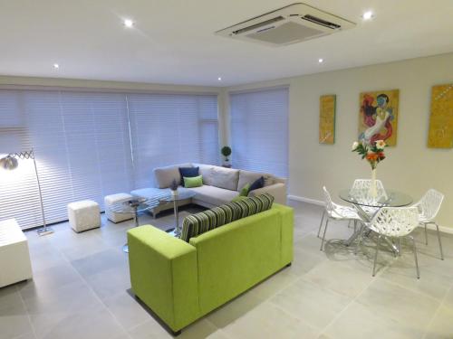 a living room with a green couch and a table at The Executive - Exclusive Self-Catering Apartments - Ezulwini in Ezulwini