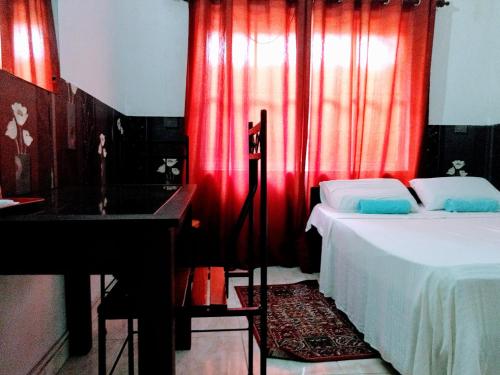 a bedroom with red curtains and a bed and a sink at Villa Two Residence in Mount Lavinia