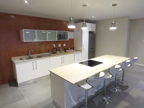 a kitchen with white cabinets and a island with bar stools at The Executive - Exclusive Self-Catering Apartments - Ezulwini in Ezulwini