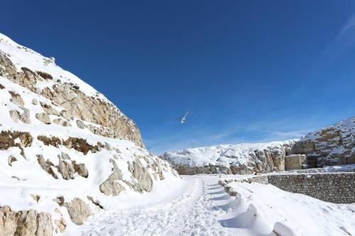 a snow covered mountain with an airplane flying over it at B&B Casabasoti in Valli del Pasubio