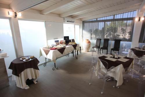 a dining room with tables and chairs and large windows at Hotel Eubea in Reggio Calabria