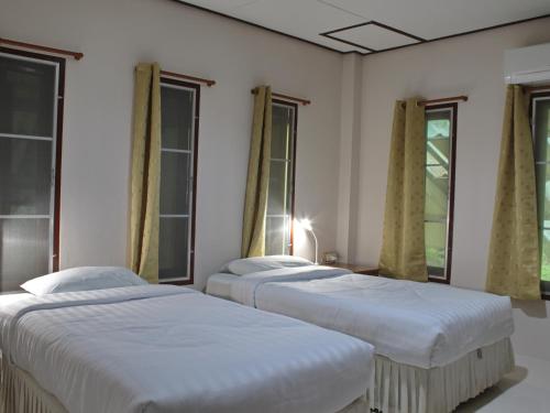 two beds in a room with windows at Baan Maka Nature Lodge in Kaeng Krachan