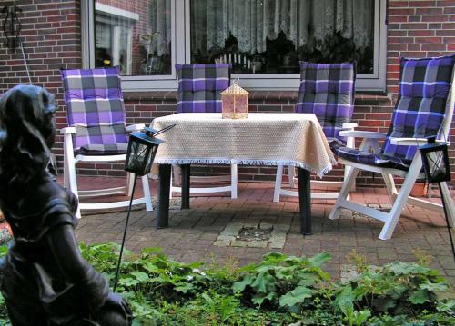 a table with purple chairs and a table and a statue at Appartements im Moormerland in Warsingsfehn