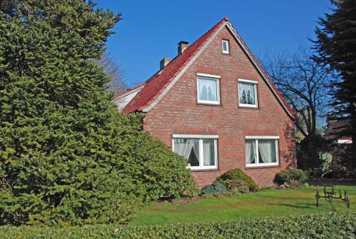 een rood bakstenen huis met witte ramen en een boom bij Appartements im Moormerland in Warsingsfehn