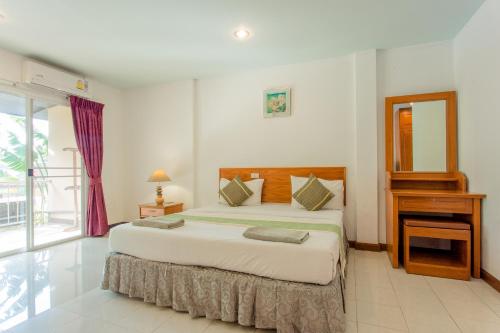 a bedroom with a large bed and a window at Surin Sunset Hotel - SHA in Surin Beach