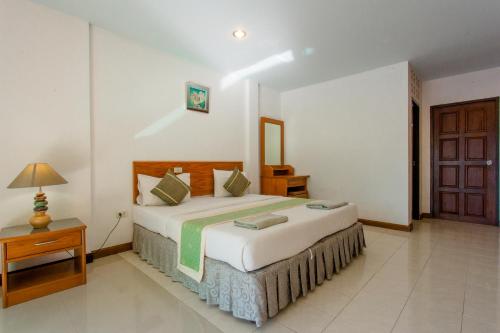 a bedroom with a bed and a table and a door at Surin Sunset Hotel - SHA in Surin Beach