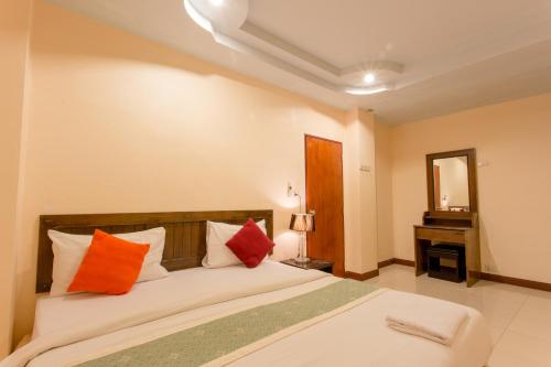 a bedroom with a bed with orange and red pillows at Surin Sunset Hotel - SHA in Surin Beach