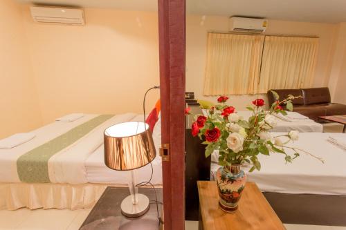 a room with a bed and a table with a vase of flowers at Surin Sunset Hotel - SHA in Surin Beach