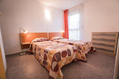 a hotel room with two beds and a window at Les Pavillons du Rooy in Salies-de-Béarn