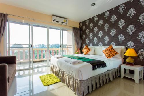 a bedroom with a large bed and a balcony at Surin Sunset Hotel - SHA in Surin Beach