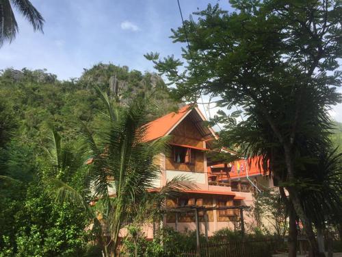 a house with an orange roof in the middle of trees at Yayee Homestay in Sai Yok