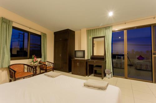 a bedroom with a bed and a television and a balcony at Surin Sunset Hotel - SHA in Surin Beach